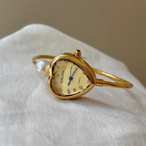 Detailed view of the heart-shaped gold dial and pearl of the SUNLIFEX bangle watch