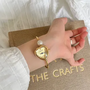 Close-up detail of a SUNLIFEX heart-shaped gold bangle watch featuring a pearl accent