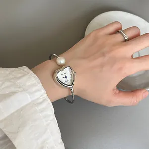 Close-up of elegant heart-shaped SUNLIFEX bangle watch with pearl detail on wrist