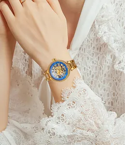 Nahaufnahme einer goldenen Skelett-Automatikuhr mit blauem Zifferblatt und Strass