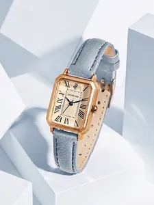 Gros plan d'une montre rectangulaire vintage dorée avec un bracelet en cuir bleu clair