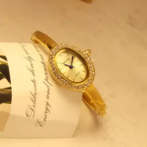 Detailansicht einer luxuriösen goldenen ovalen Armbanduhr mit Strass-Lünette