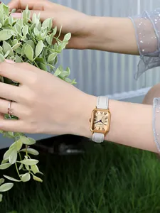 Montre rectangulaire dorée élégante pour femme avec bracelet cuir blanc et chiffres romains.