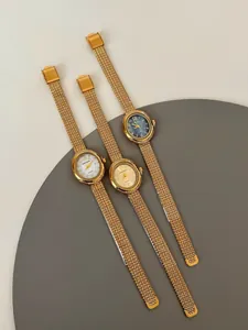Detailed view of three luxury gold-toned quartz watches with elegant mesh bracelets.