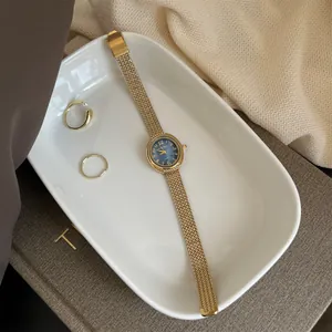 Close-up of elegant gold quartz watch with blue dial in a ceramic tray