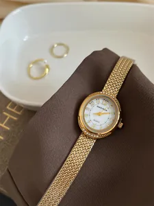 Close-up of a gold-toned luxury quartz watch with a braided metal strap and crystal bezel.