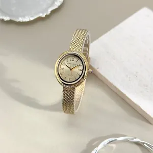 Close-up of luxury gold watch with woven metal strap and diamond-encrusted bezel