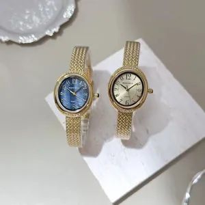 Pair of luxury gold mesh strap quartz watches presented on a white marble background