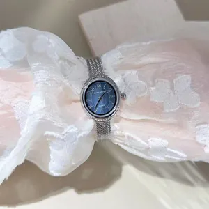 Close-up of an elegant silver mesh strap women's watch featuring a blue dial and diamond bezel