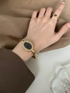Elegante goldene ovale Armreif-Uhr mit glitzernder Strass-Lünette für Damen am Handgelenk
