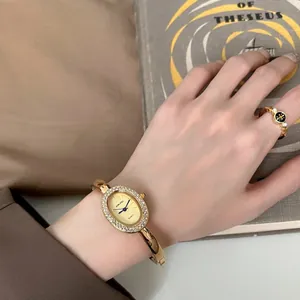 Elegante Retro-Goldarmreif-Uhr mit Strass-Lünette am Handgelenk für Damen getragen