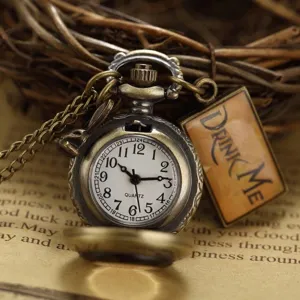 Close-up view of a vintage bronze pocket watch with Alice in Wonderland Drink Me tag