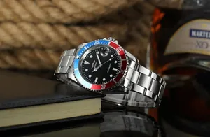 Macro view of WINNER men's automatic watch with red-blue bezel resting on a notebook