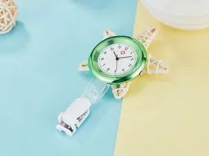 Close-up view of a green quartz nurse watch with a white clip and red cross logo