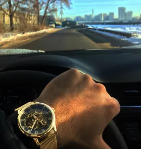 Nahaufnahme einer goldenen Forsining Skelett-Mechanikuhr mit Mesh-Armband am Handgelenk.