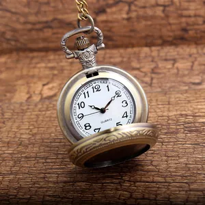Detailed view of an open antique bronze pocket watch with an engraved floral lid.