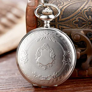 Primer plano de reloj de bolsillo vintage plateado con intrincados grabados florales.