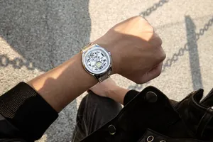 Detailopname van heren quartz horloge met geskeletteerde wijzerplaat en zilveren band.