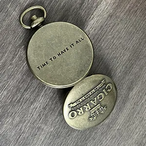 Detailopname van een antieke koperen zakhorloge-box voor vaste parfum met gravure
