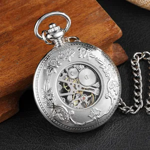 Gros plan d'une montre à gousset mécanique argentée avec gravures florales