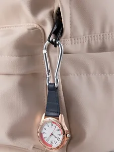 Klein horloge met karabijnhaak en lederen band, bevestigd aan een beige rugzak