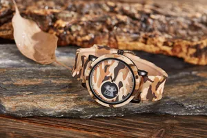 Macro detail of a camouflage sports watch featuring a silicone strap on a natural rock.