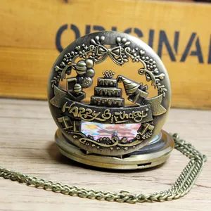 Detailopname van bronzen zakhorloge met uitgehold Happy Birthday-ontwerp, taart en ballonnen.