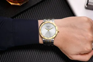 Primer plano detallado de un reloj de cuarzo para hombre con bisel dorado en muñeca