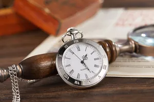 Close-up of vintage quartz pocket watch with white dial and elegant Roman numerals