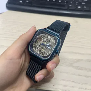 Close-up of a men's automatic mechanical watch with a blue square skeleton dial.
