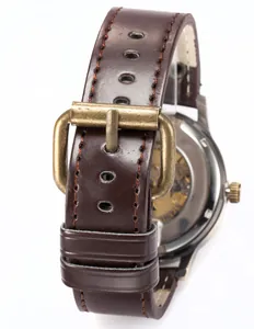 Detalle de la correa de cuero marrón con hebilla de bronce antiguo para reloj mecánico.