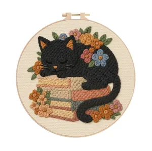 Detailed view of finished black cat embroidery on a stack of books with floral accents