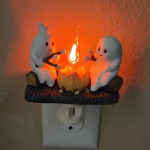 Close-up of cute ghosts sitting by flickering campfire Halloween plug-in night light.