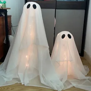 Detailed view of two white glowing Halloween ghost decorations with warm LED lights