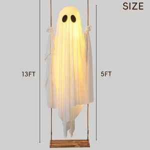 Large glowing Halloween hanging white ghost on a wooden swing for outdoor yard decor