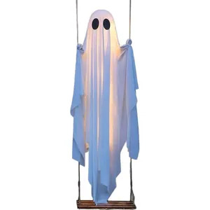 Large glowing white Halloween ghost decoration hanging on a wooden swing for outdoor