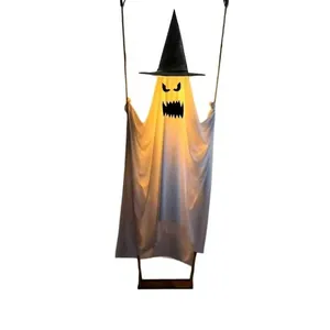 Close-up of a glowing Halloween hanging ghost with a black witch hat on a swing
