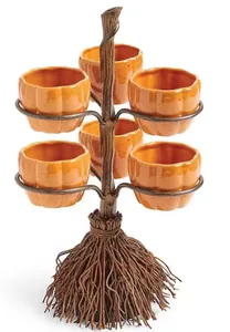 Detalle del soporte de aperitivos con forma de escoba de Halloween y tazas de calabaza.