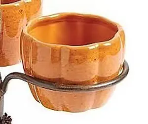 Primer plano de una taza de calabaza decorativa en un soporte de metal negro vintage