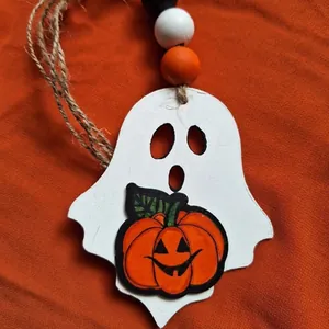 Detailed view of a handcrafted wooden Halloween ghost ornament with an orange pumpkin