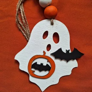 Detailed macro view of handcrafted wooden Halloween ghost ornament with pumpkin and bats