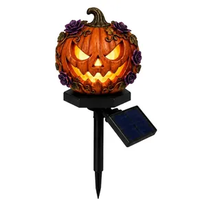 Primo piano della lampada solare a forma di zucca di Halloween con rose viola e viti