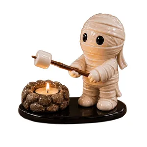 Detail einer niedlichen Mumienfigur beim Rösten von Marshmallows über dem Teelichthalter