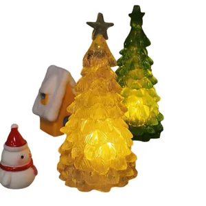 Detail of glowing crystal Christmas tree night lights with snowman and cabin props.