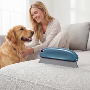 Strumento blu in silicone per rimuovere i peli di animali su un divano grigio con un cane
