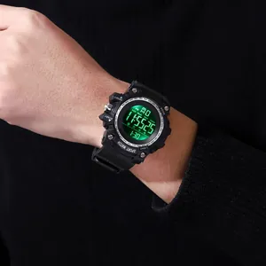 Detail shot of a black digital sports watch with bright green LED backlight on a wrist.