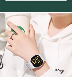 Close-up of a stylish white waterproof LED digital sports watch worn on a wrist holding a cup