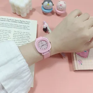 Nahaufnahme einer rosa quadratischen Quarzuhr am Handgelenk in einer süßen Umgebung.