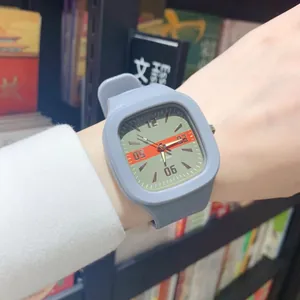 Close-up of a stylish grey square quartz watch with date display worn on wrist.
