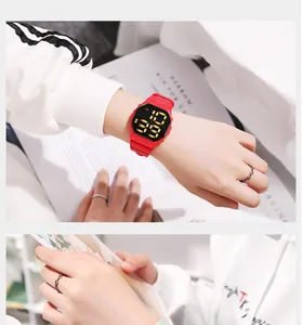 Detail of a vibrant red digital sports watch with luminous LED display on wrist.